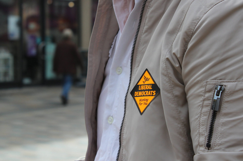 A person on a street showing a Liberal Democrat badge