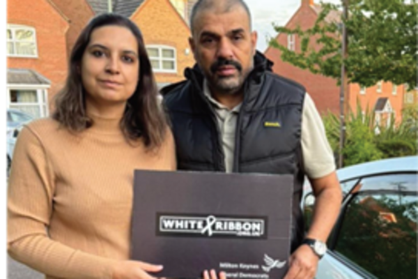 Saleena Raja and Asad Raja holding a banner showing their support for the White Ribbon Campaign